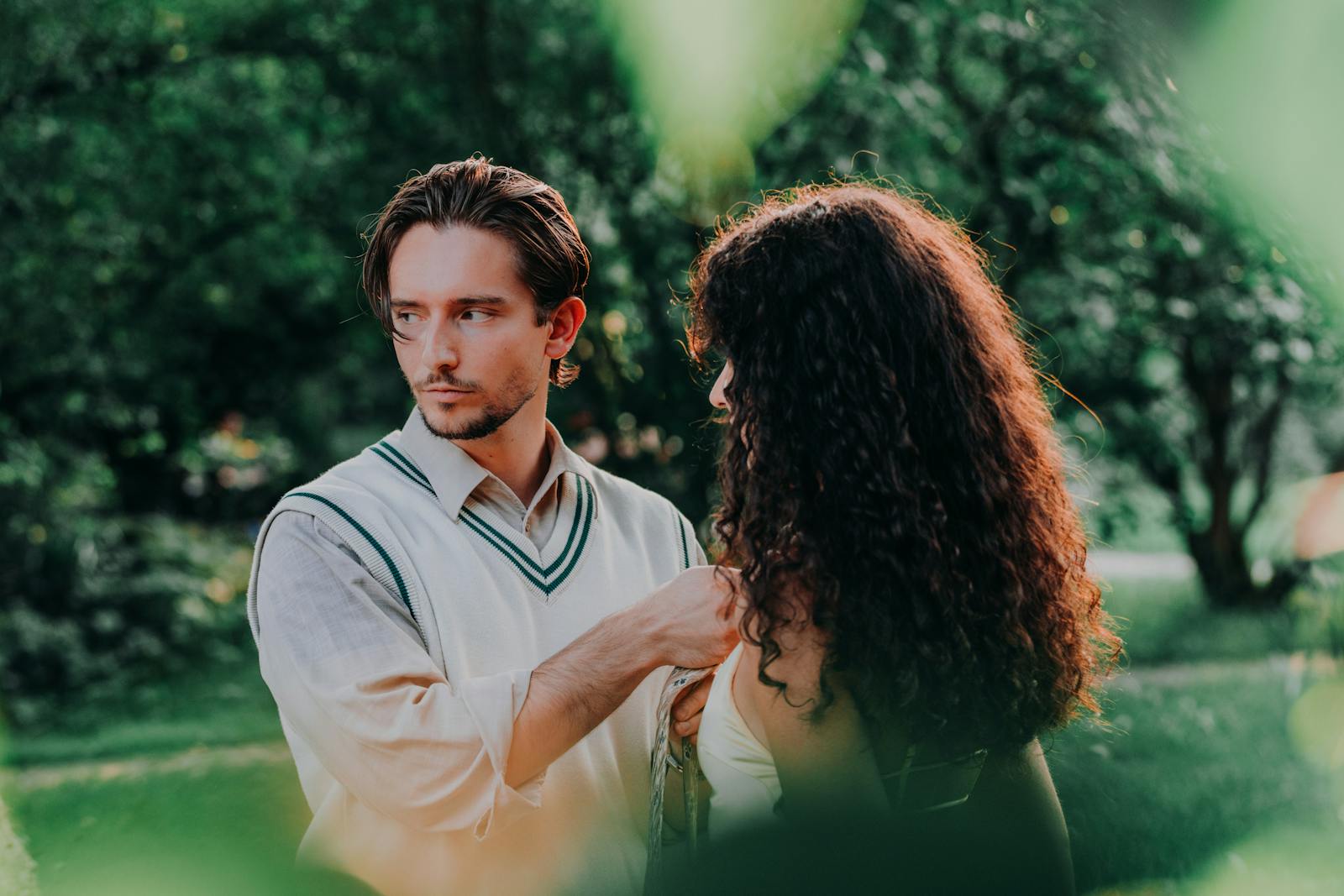 A young couple shares a moment in a lush, sunlit summer garden.